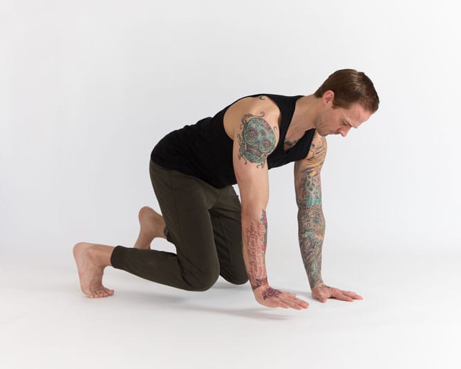 Man in Beast position, with opposite hand and foot hovering above the ground